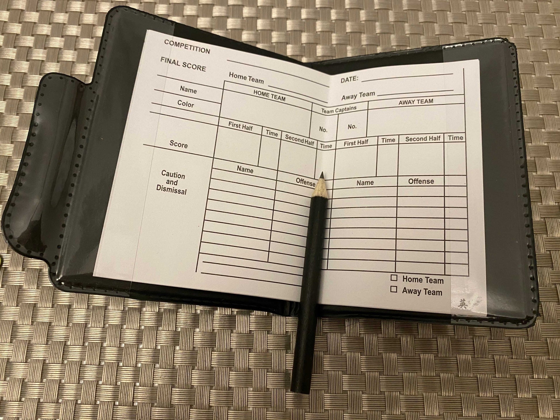 Soccer referee tool scorebook open with pencil placed on woven mat featuring apple pencil apple keyword
